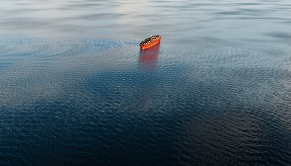 A cargo container ship navigates calmly across open ocean water, carrying numerous shipping containers.