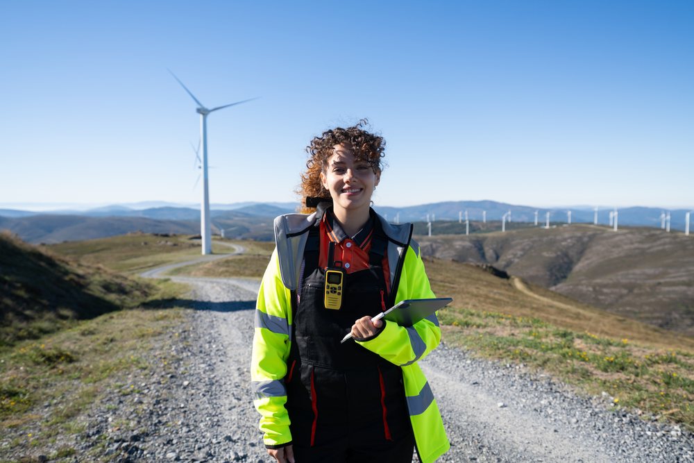 Woman engineer holds a tablet and radio on a mountain road at a wind farm, sustainability, renewable energy, Galicia, Spain.