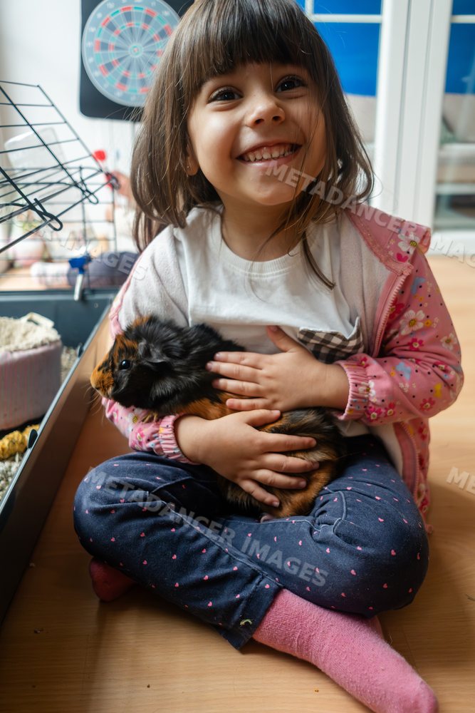 A white girl happily holds a guinea pig indoors in Madrid, Spain