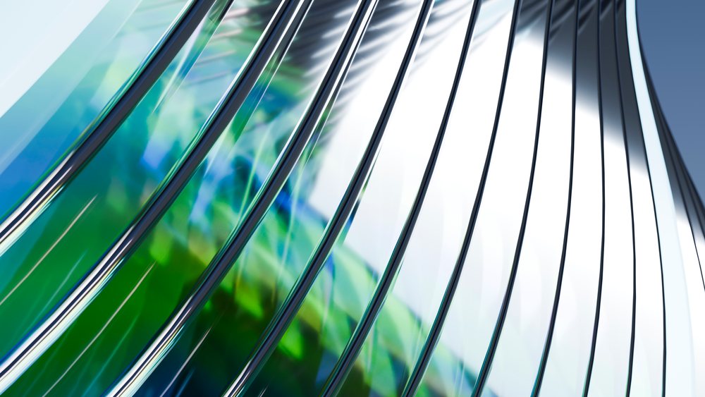 Curved transparent glass with green and blue reflections forming an abstract architectural pattern.