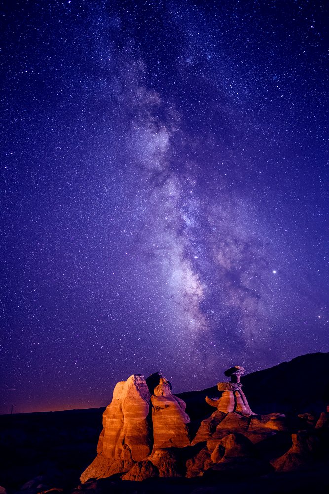 Milky Way galaxy shines brightly over illuminated rock formations in Utah's Buckskin Gulch slot canyon at night, USA.