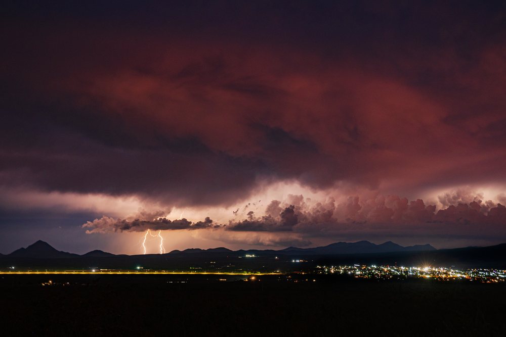 Lightning bolts strike over mountains during a monsoon storm at night, Storm Chasing, Weather, Environmental Issues, Bisbee, Arizona, USA.
