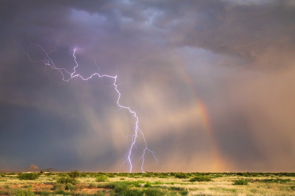 Lightning strike with a Rainbow over green grassland during a storm, Chasing, Weather, Environmental Issues, Douglas, Arizona, USA.