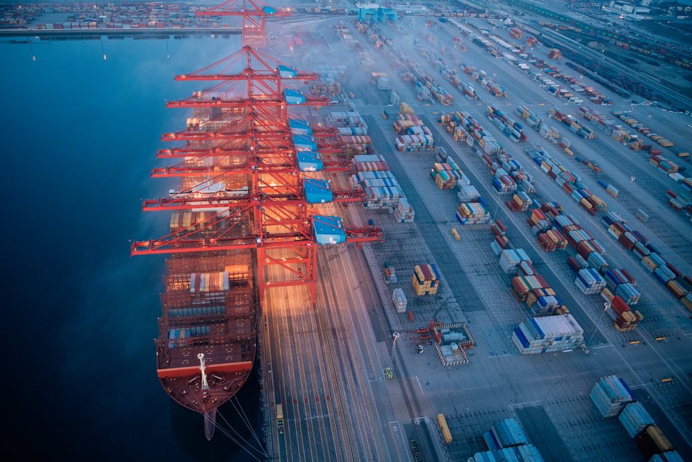 Container ship docked at cargo cranes in the Port of Long Beach with containers stacked in the port terminal, CA, USA.