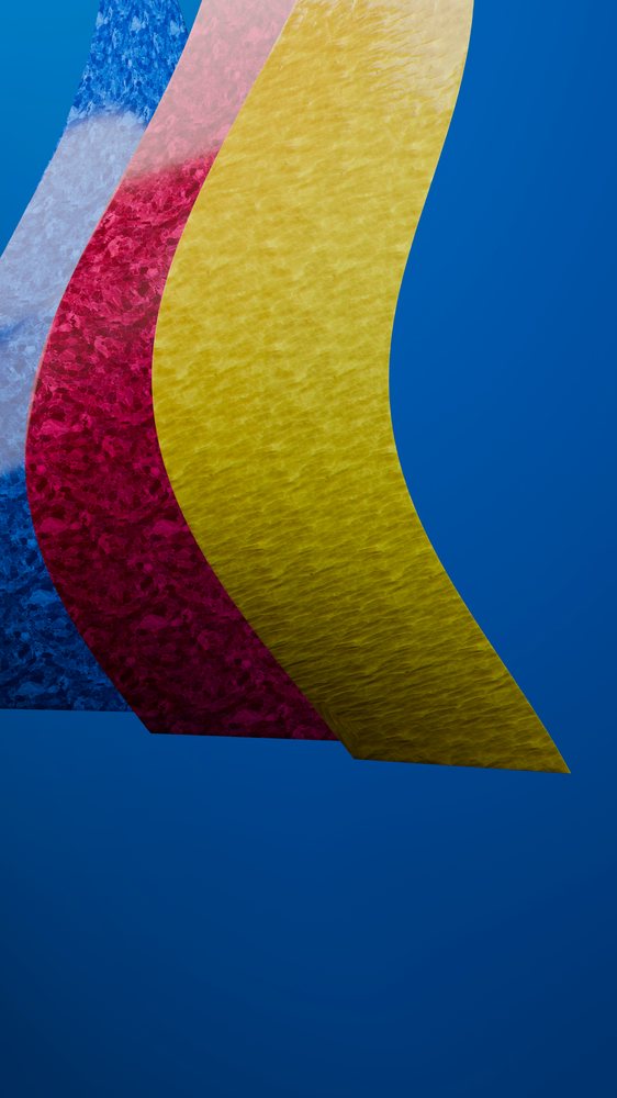 Three colorful curved sheets with patterned texture arranged against a blue background in an abstract artistic composition.