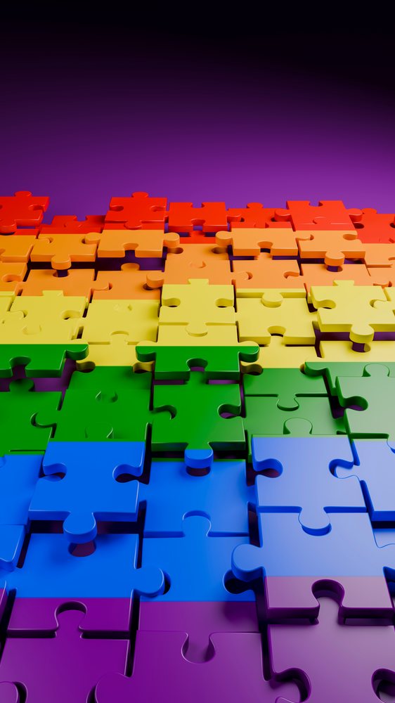 Colorful rainbow gradient interlocking jigsaw puzzle pieces partially assembled on a smooth reflective surface.