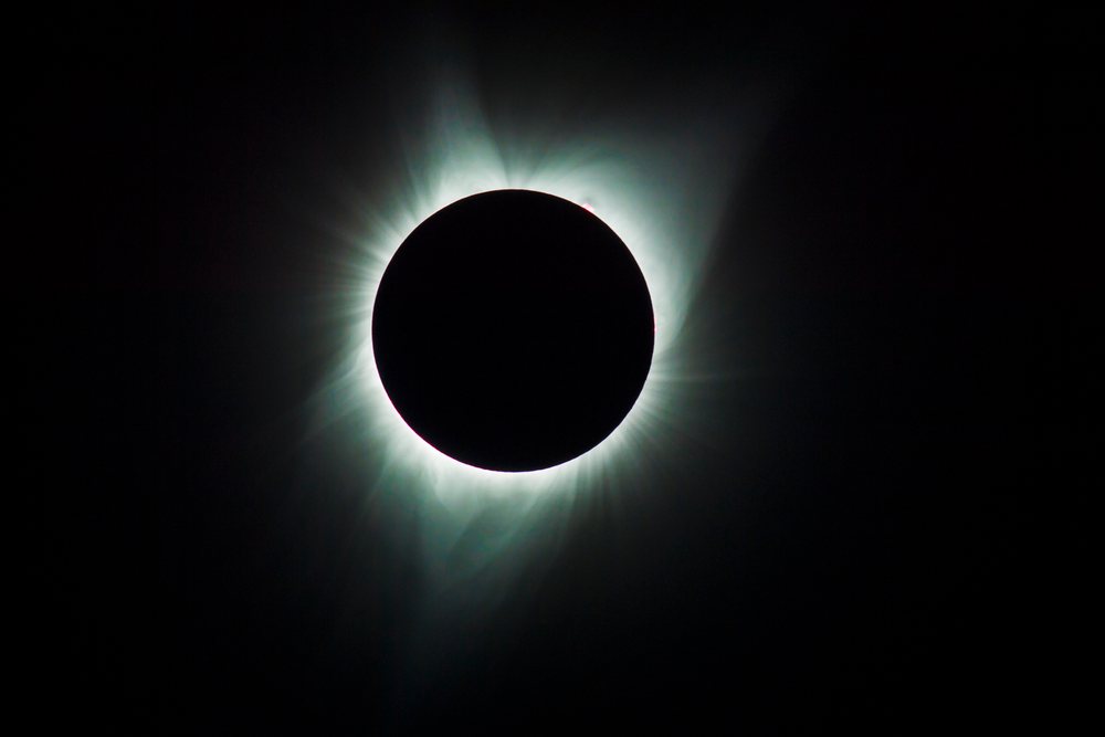 Total solar eclipse with bright glowing corona and moon silhouette in dark sky over, Los Angeles, USA.