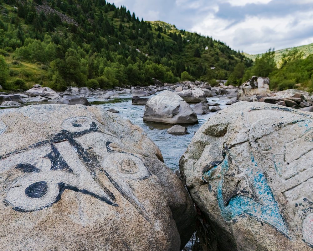 Mani Rocks painted with Tibetan script lie in a flowing River, Tagong, Sichuan Province, People's Republic of China.