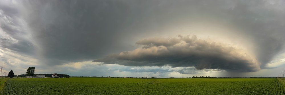 Supercell thunderstorm cloud forming over flat green farmland with power lines in Tornado Alley, Weather, Environmental Issues, Storm Chasing, Charleston, Illinois, USA.