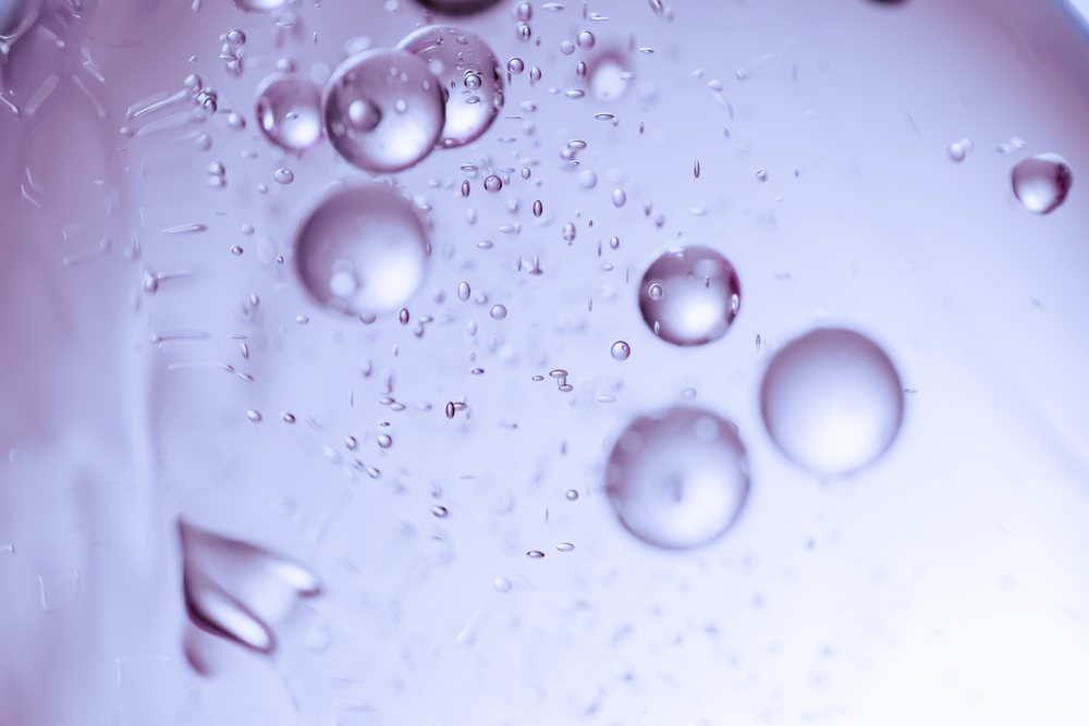 Water bubbles suspended in a liquid with an abstract purple background.