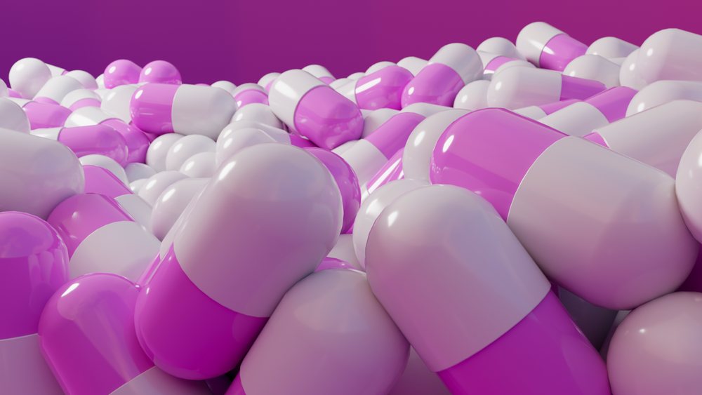 Close-up of a pile of purple and white capsule pills for medical use.
