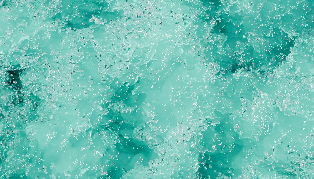Bubbling clear blue water with sparkling droplets and dynamic movement.