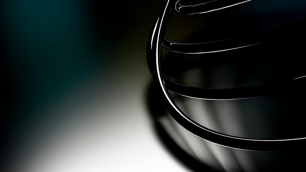 Close-up of a shiny metal whisk utensil with wire loops against a dark background reflecting light.