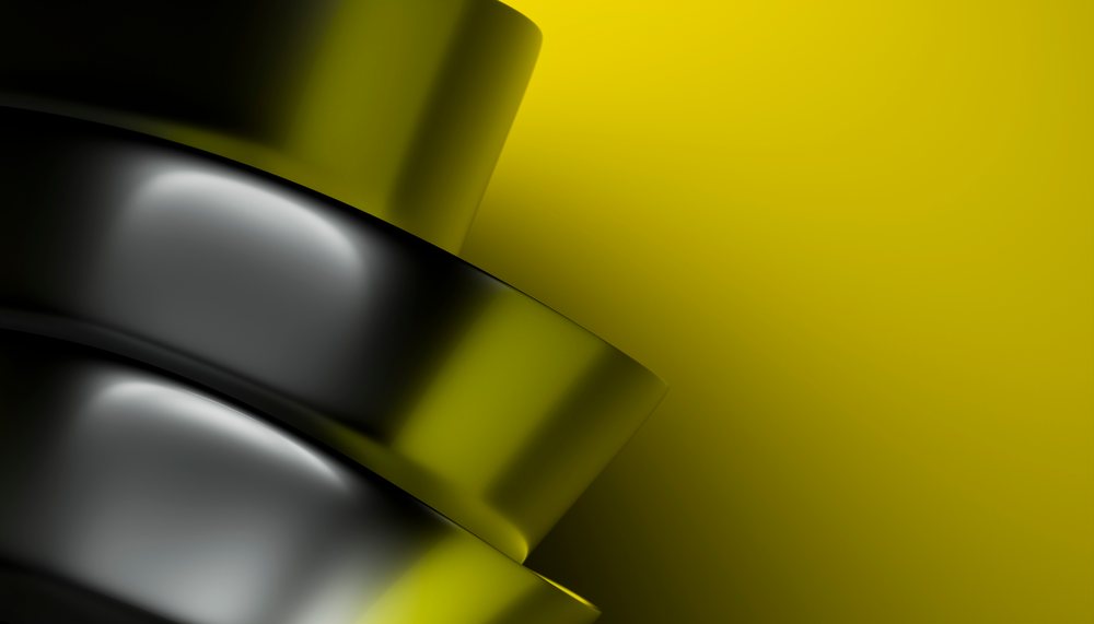 Shiny black metallic buttons stacked against a smooth yellow background in a studio setting.