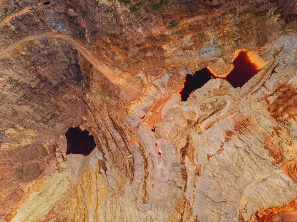Aerial view of the Bisbee Copper Mine open pit with rust-colored mining ponds and rock formations at dusk, Storm Chasing, Weather, Environmental Issues, Arizona, USA.