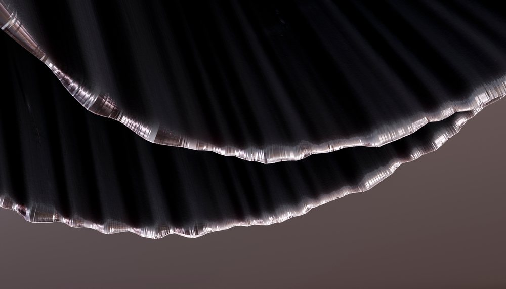 Close-up of dark fabric showing folded pleats with detailed edges and textured textile surface.