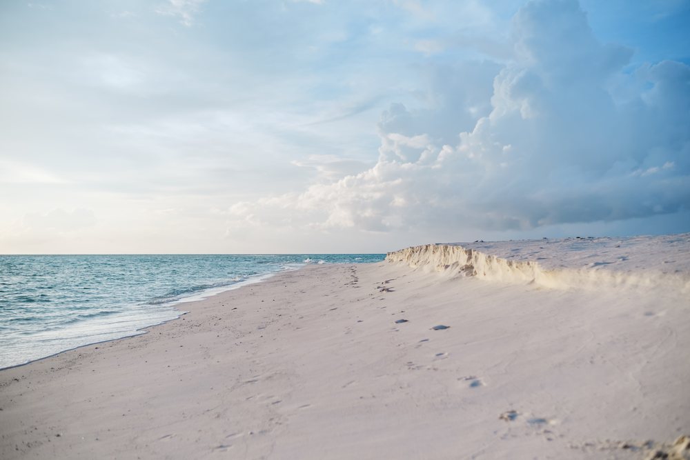 A serene sandy beach with footprints along the shoreline in a beach