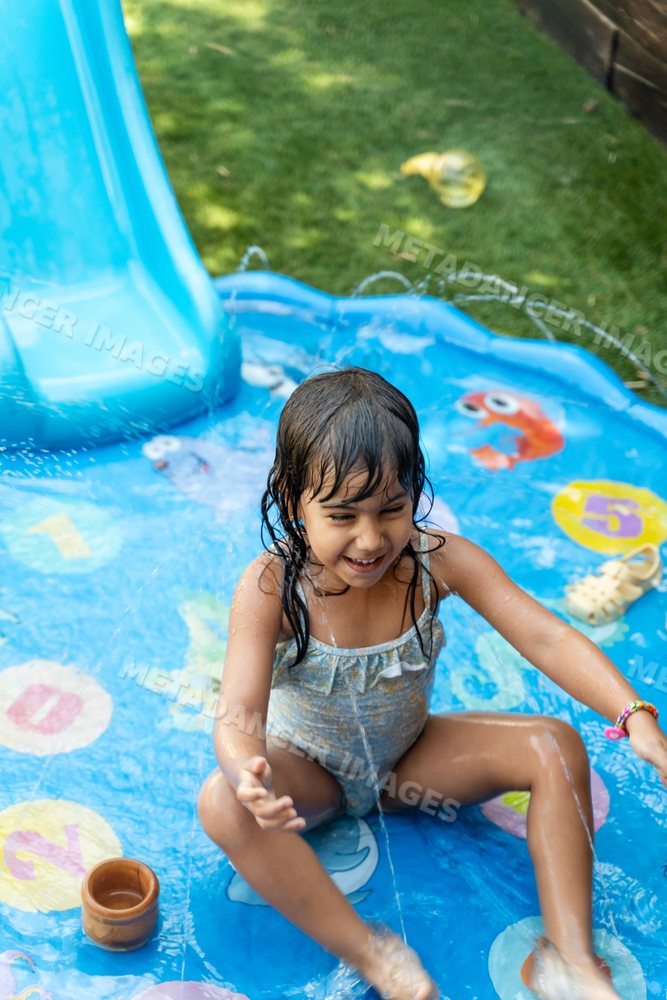 A white girl playing and splashing water in a backyard inflatable pool