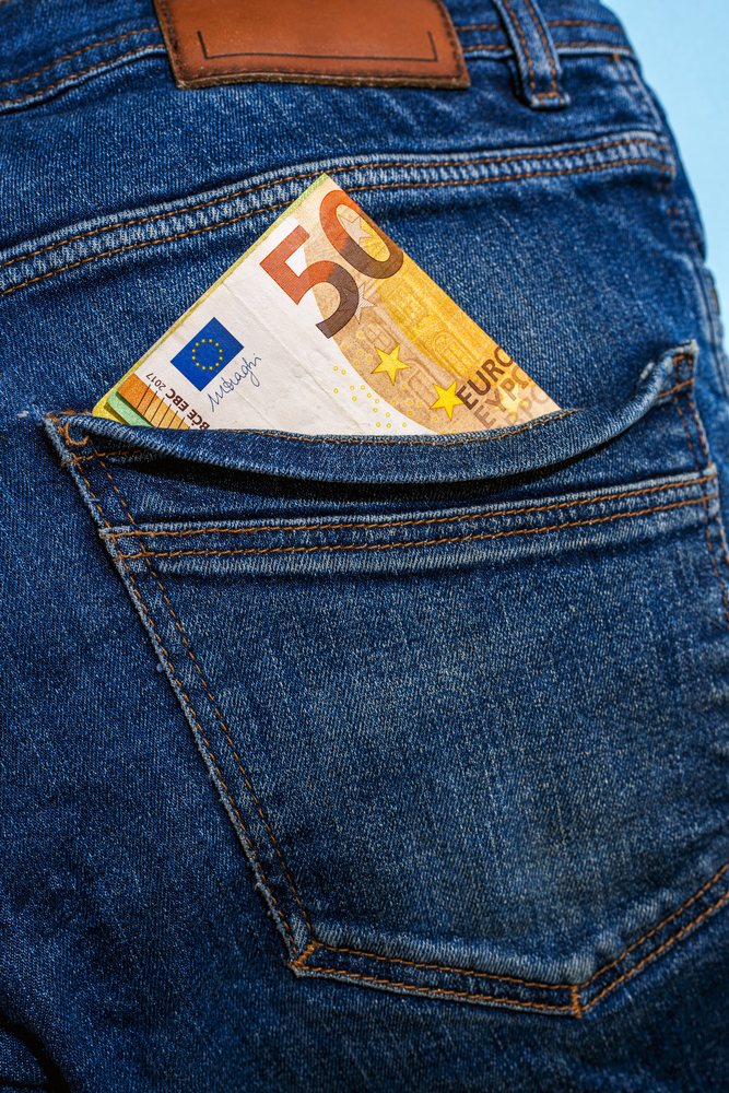 Folded 50 euro note partially inserted in the stitched back pocket of blue denim jeans, Studio Shot.