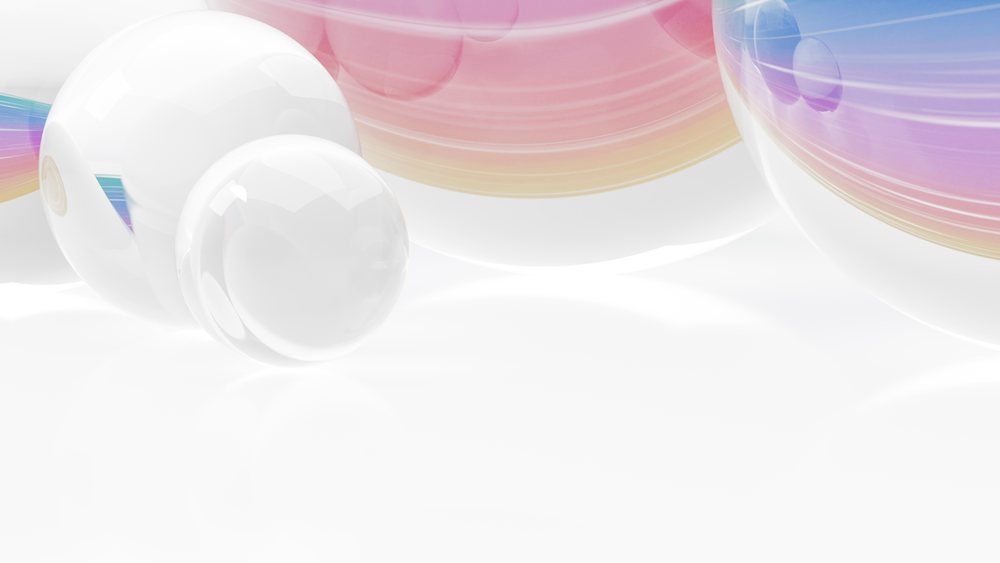 Transparent glass spheres with colorful swirl patterns resting on a white reflective surface in a minimalist setting.