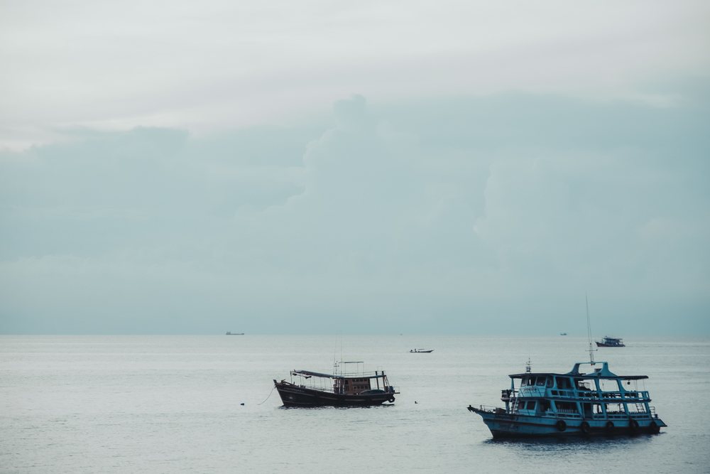 Fishing boats anchored on calm sea under a cloudy sky in the Philippines during daytime.