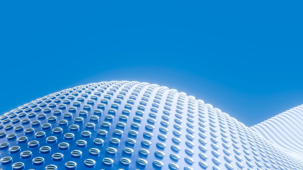 Rows of glass marbles cover a smooth wavy surface reflecting the blue sky in an abstract modern design.