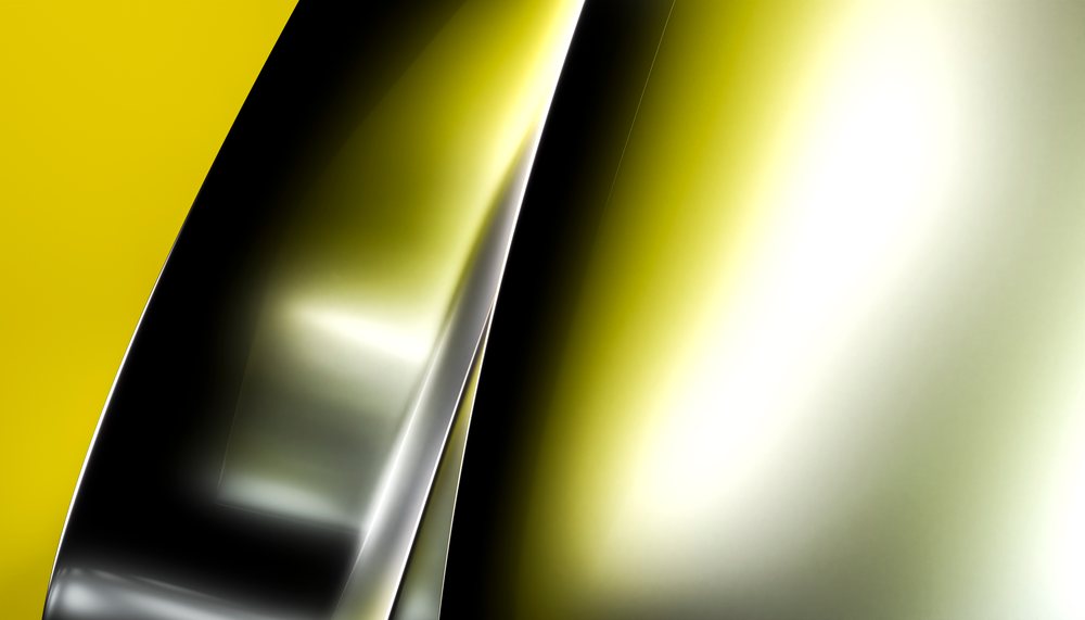 Close up of a shiny reflective metal surface with yellow and silvery highlights.