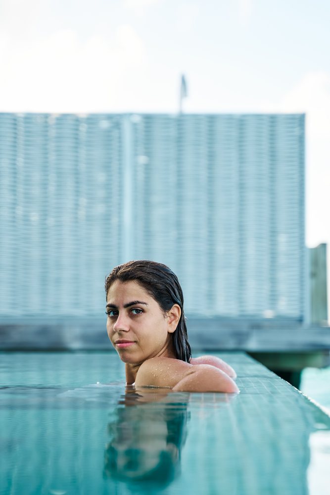A white woman relaxes in a swimming pool by the pool edge