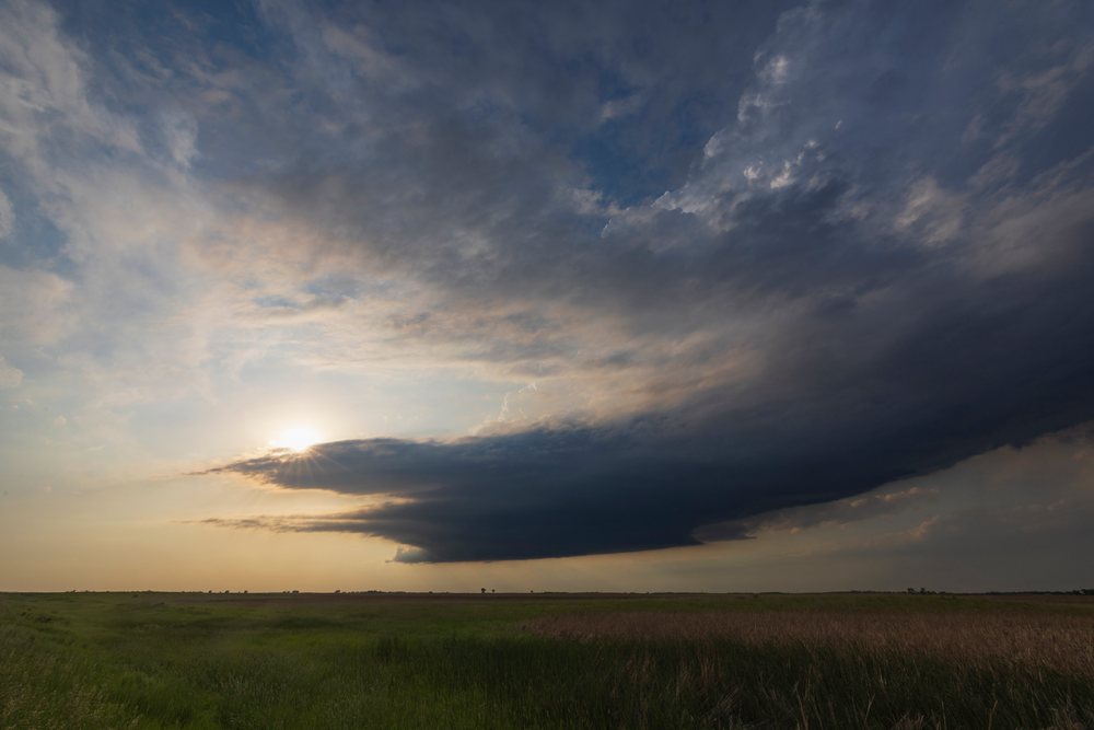 Supercell storm cloud forms over an open grassy field at sunset during storm chasing, Montpelier, North Dakota, USA.