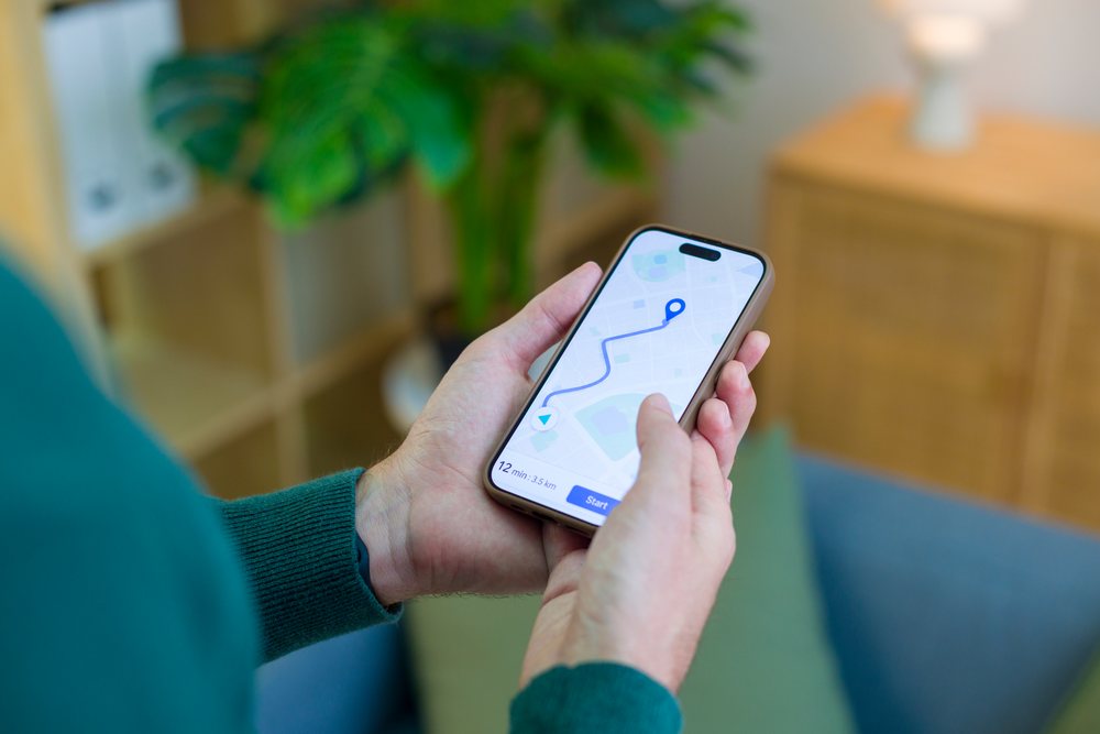 Smartphone held in hand showing a navigation app with a route displayed indoors, technology, young adult, home.