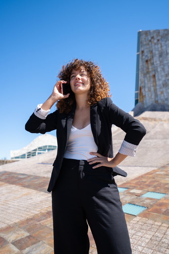 Businesswoman talking on phone outdoors in front of modern architecture in Santiago de Compostela, traveling executive, Spain, Antiago De Compostela.
