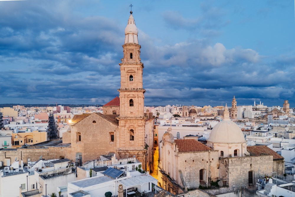 Cathedral basilica of Maria Santissima della Madia with bell tower and dome overlooks old Mediterranean town of Monopoli at dawn, Puglia, Italy.