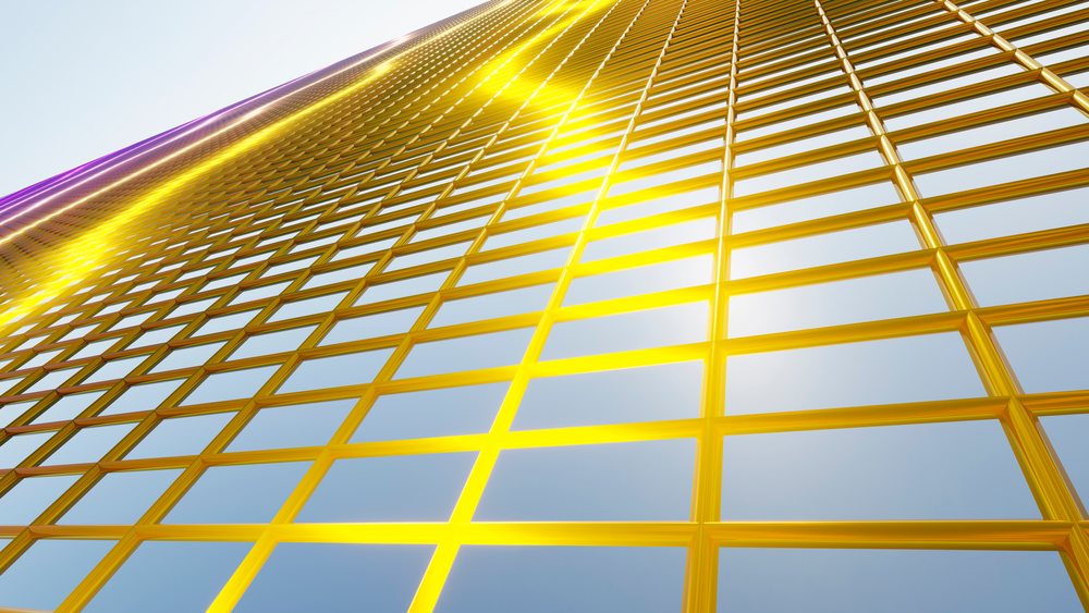 Golden grid with reflective yellow frames on modern architectural structure under clear blue sky.