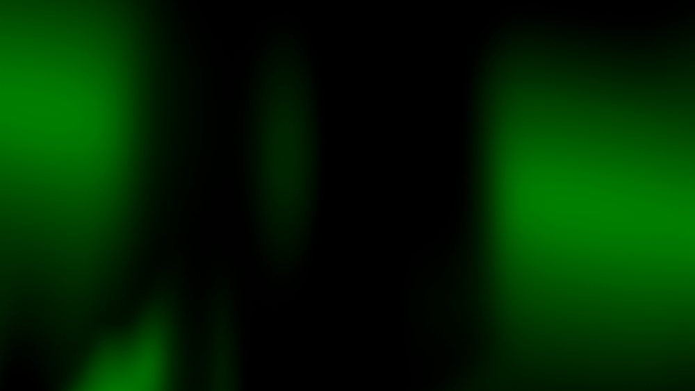 Green blurred glowing circular bokeh lights create an abstract effect on a dark background.