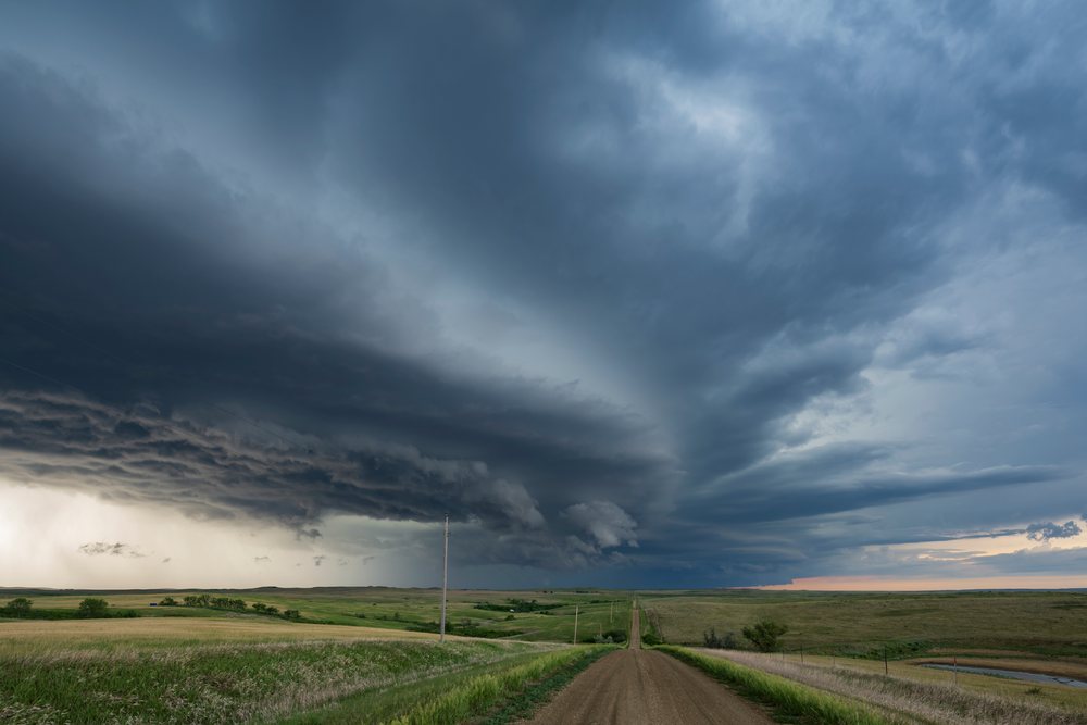 Storm cloud formation over a country dirt road with grassland fields and electric poles in South Dakota's Great Plains during a thunderstorm, Storm Chasing, Weather, Environmental, Wood - Butte Greek, USA.