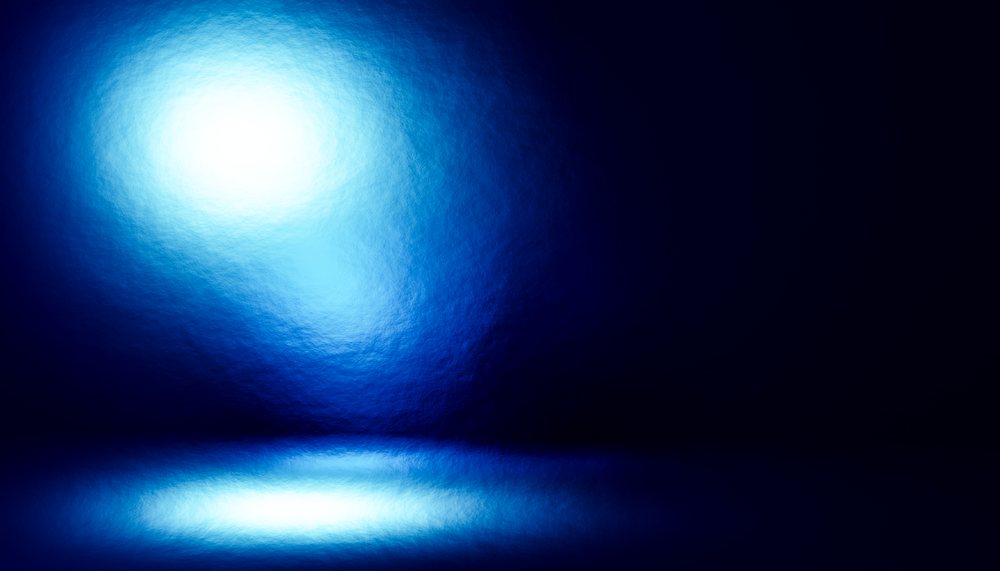 Blue bright light reflecting on a dark, shiny surface creating an abstract glowing effect.