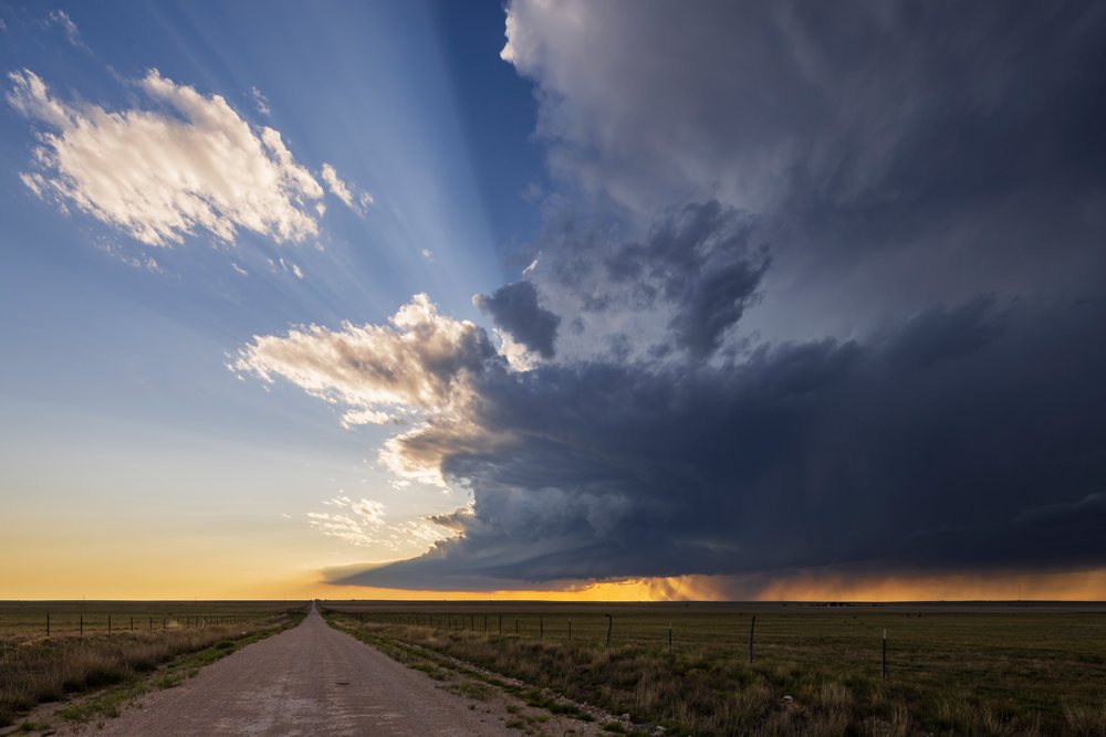 Supercell thunderstorm forming over rural grassland at sunset with dramatic clouds and rain shafts visible, Storm Chasing, Amistad, New Mexico, USA.