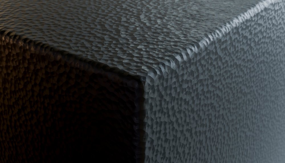 Closeup of a textured table corner showing a patterned surface with contrasting shadows under lighting.