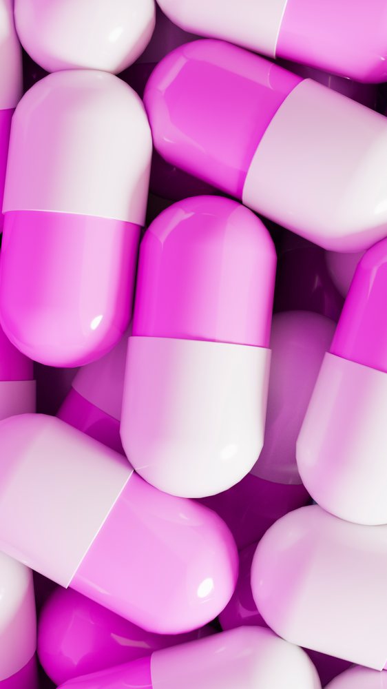 Close-up view of pink and white capsule pills clustered together illustrating medication and pharmaceutical concepts.
