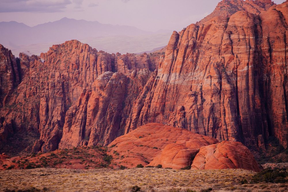 Red sandstone rock formations and rugged desert cliffs in Utah's red Cliffs Desert State Park at sunset with dry vegetation, Snow Canyon, USA.
