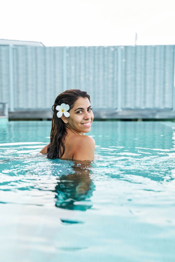 A white woman smiling while swimming in a pool