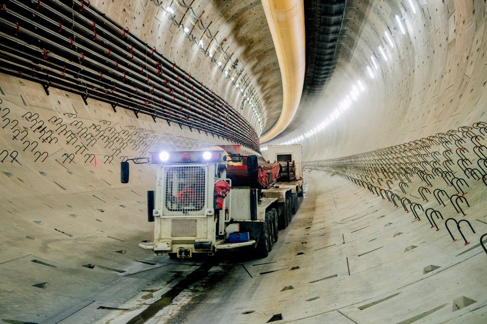 A construction vehicle moves through a large concrete-lined tunnel during drilling work, USA.