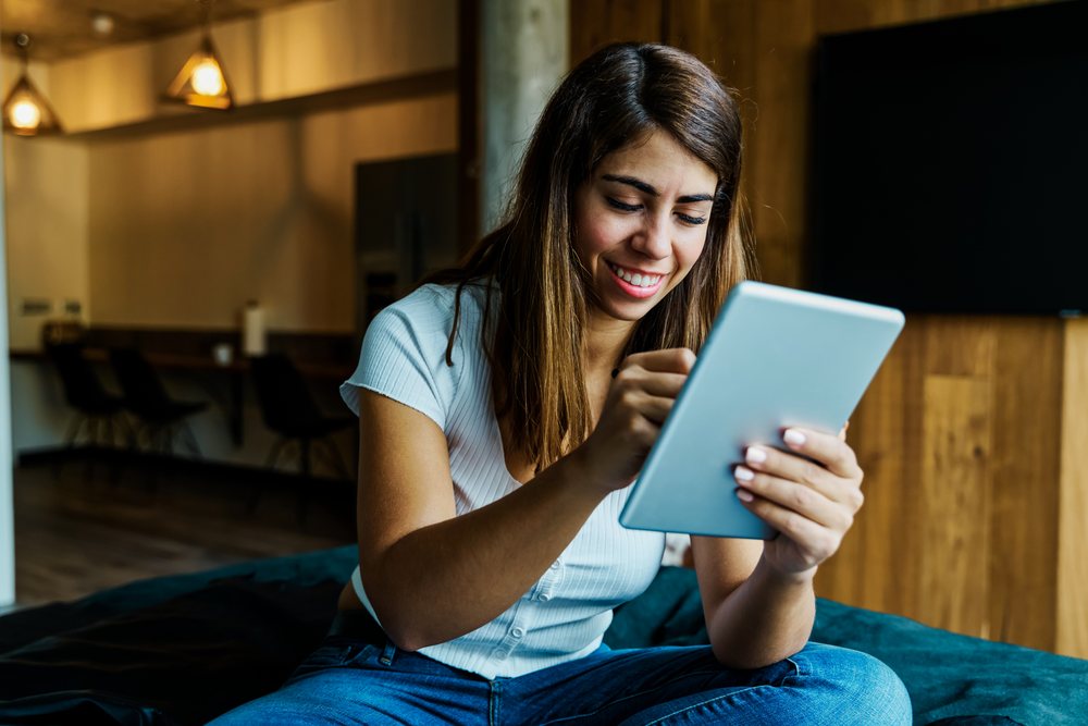 A woman smiling while using a tablet indoors in a cozy Iceland setting