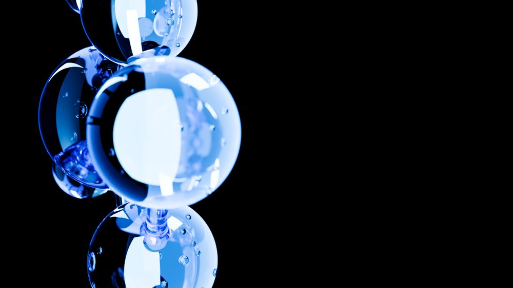 Close-up view of a cluster of glowing blue transparent bubbles with reflections and water droplets.
