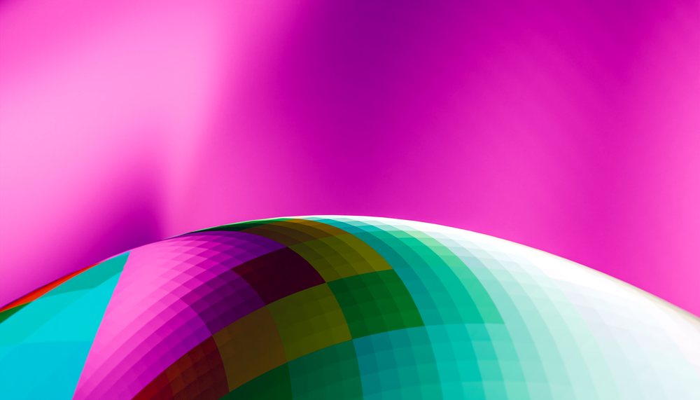 A colorful, tiled dome is featured against a vibrant pink background showcasing an abstract architectural design.