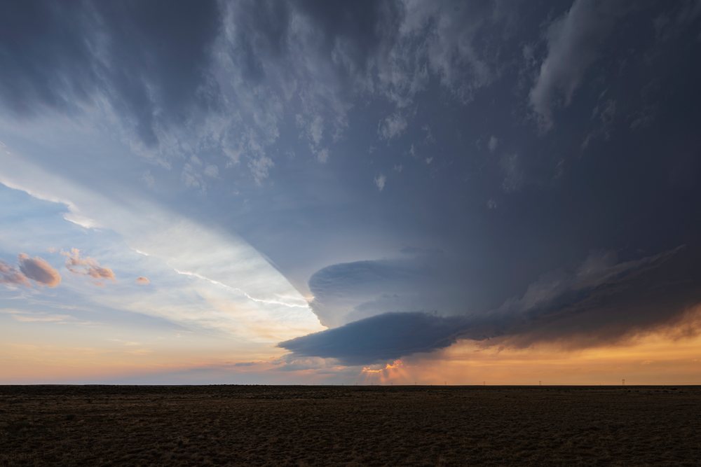 Storm clouds gather over a prairie grassland at sunset, creating a dramatic weather scene with sun rays filtering through the clouds, Storm Chasing, Environment, Olney Springs, Colorado, USA.