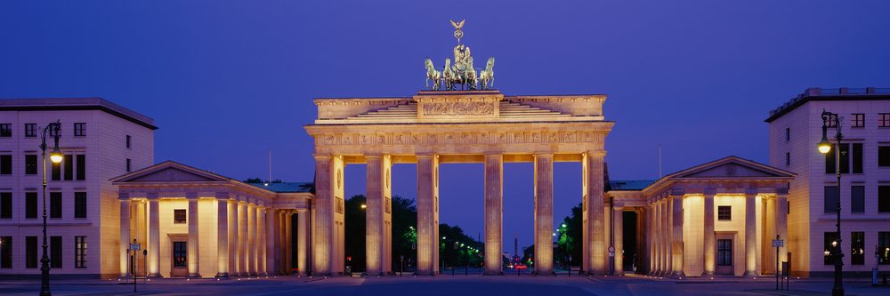 Brandenburg Gate landmark illuminated at dusk with its quadriga statue and neoclassical columns.