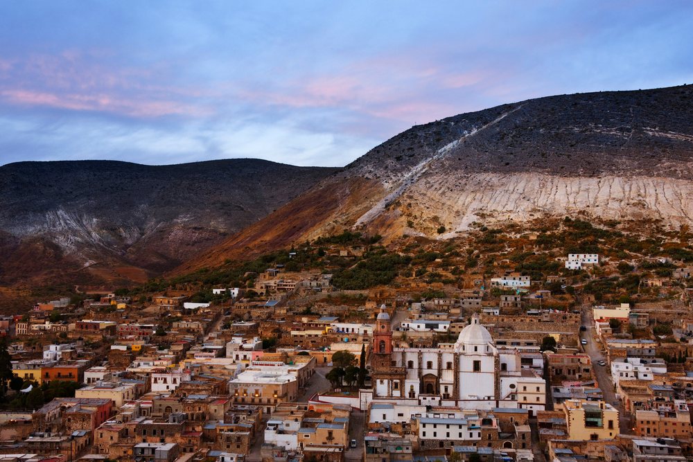 Real de Catorce town with its church and buildings at sunset beneath mountain hills, San Luis Potosi, Mexico.