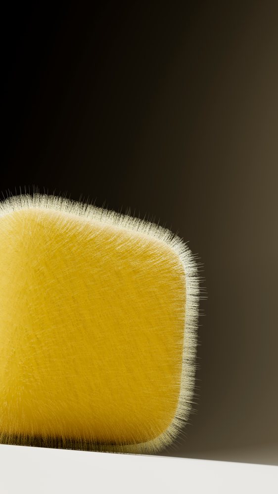 Yellow cleaning sponge with fuzzy bristle edges resting on a flat surface against a gradient background.