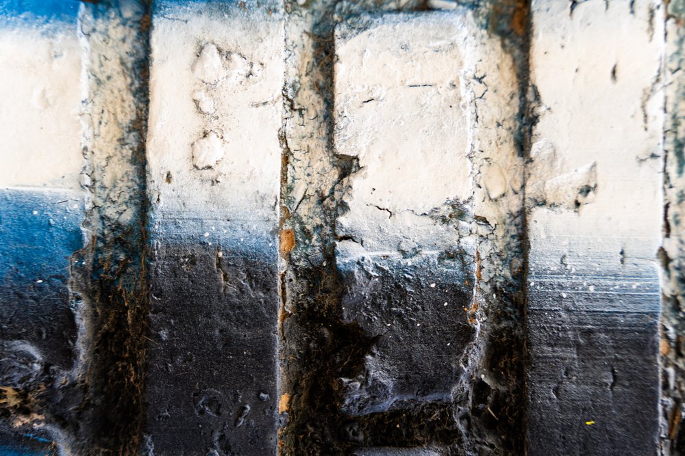 Close-up of a weathered concrete surface with layered gray, blue, and earth tone paint showing cracks and wear, texture, abstract texture, background, wallpaper, Spain.